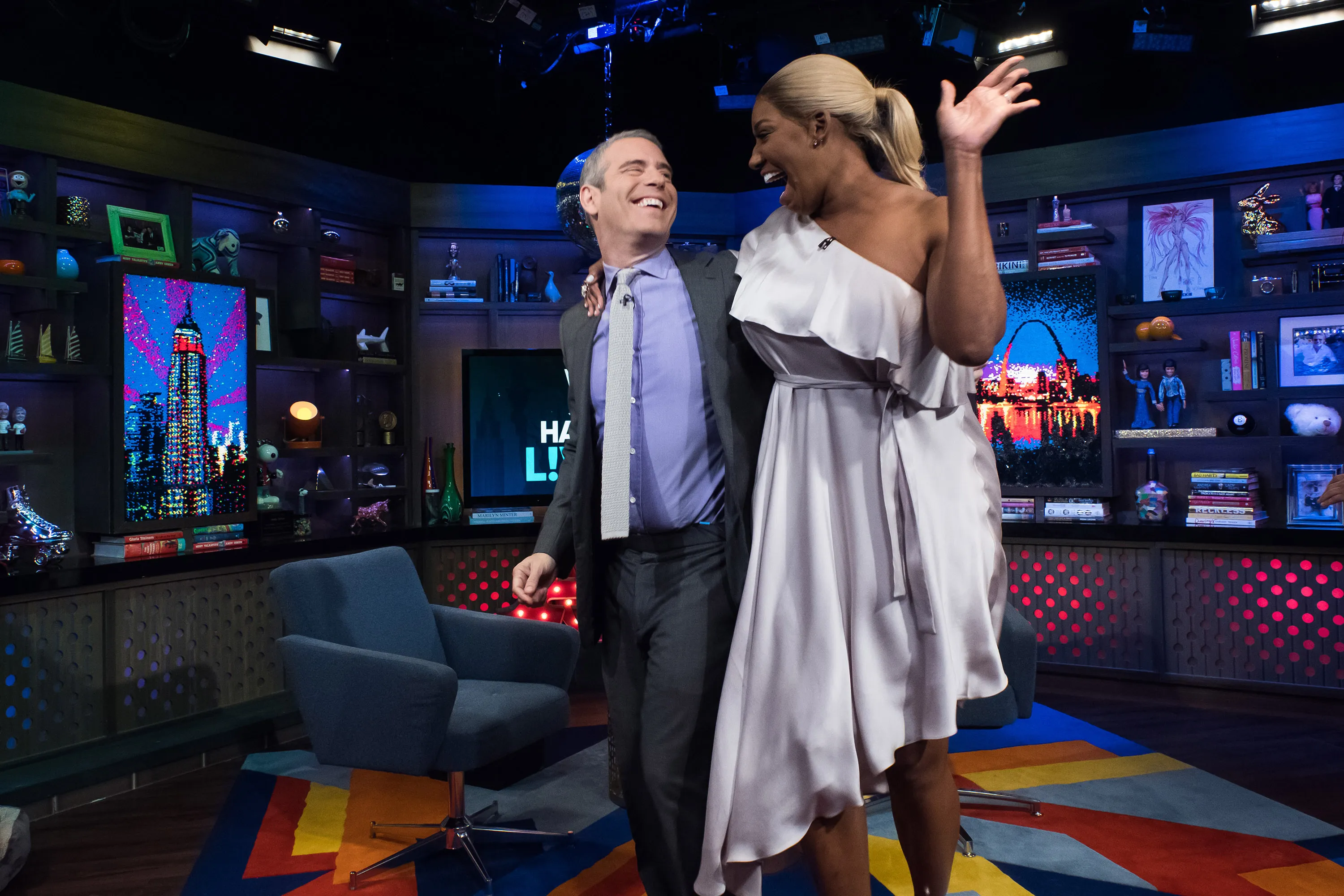 Andy Cohen and NeNe Leakes laughing and hugging on the set of a talk show.