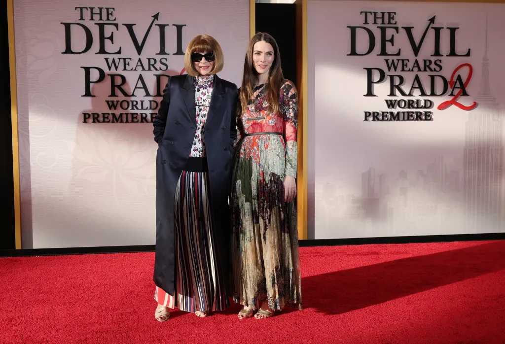 Anna Wintour, in a black coat, sunglasses and multi-colored dress, and Bee Carrozzini, in a multi-colored dresse, at 
