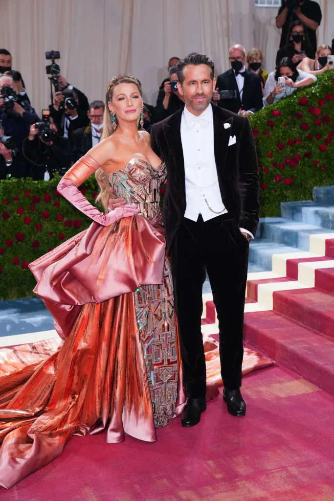 Blake Lively in a rose gold gown with an embellished bodice and long gloves, and Ryan Reynolds in a black velvet suit.