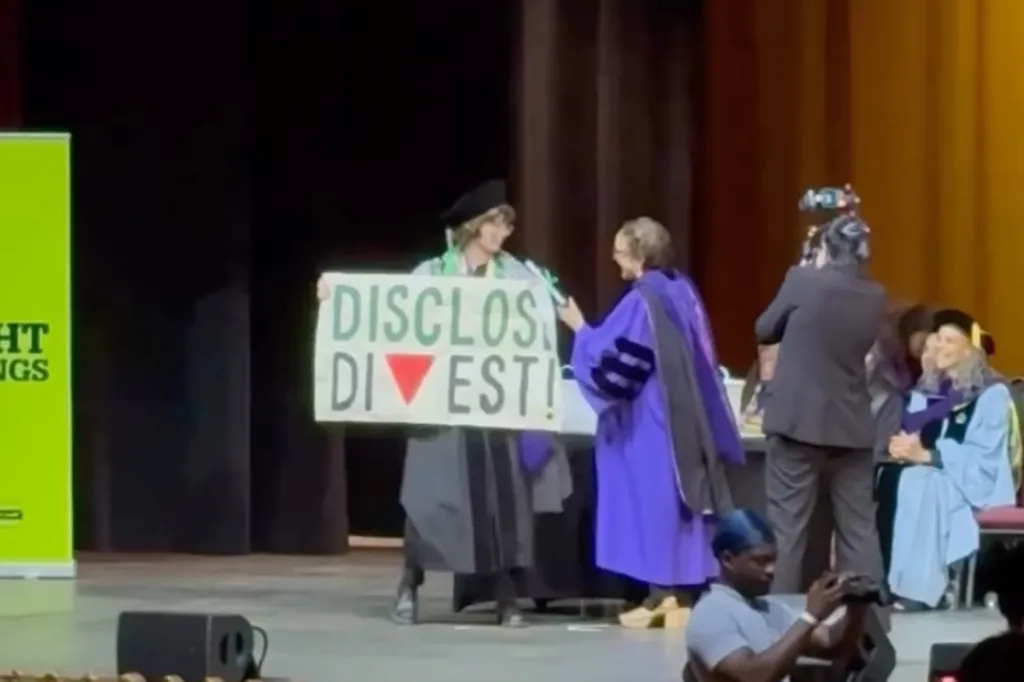 A graduating student holding a sign that reads