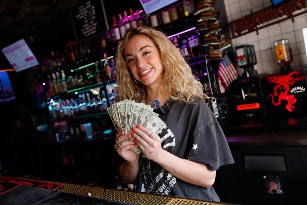 Lexie Di Chellis smiling while holding a fan of money at The Naughty Pig.