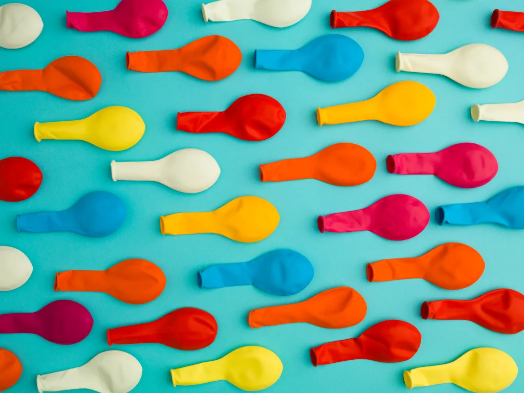 Arranged pattern of colorful deflated balloons on a blue background.