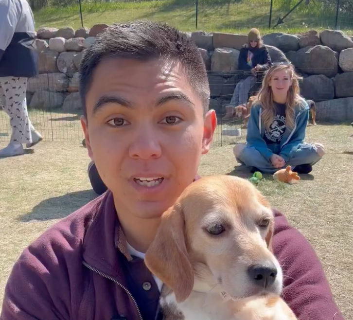 Dean Guzman Wyrzykowski holding a beagle, with others and dogs in the background.
