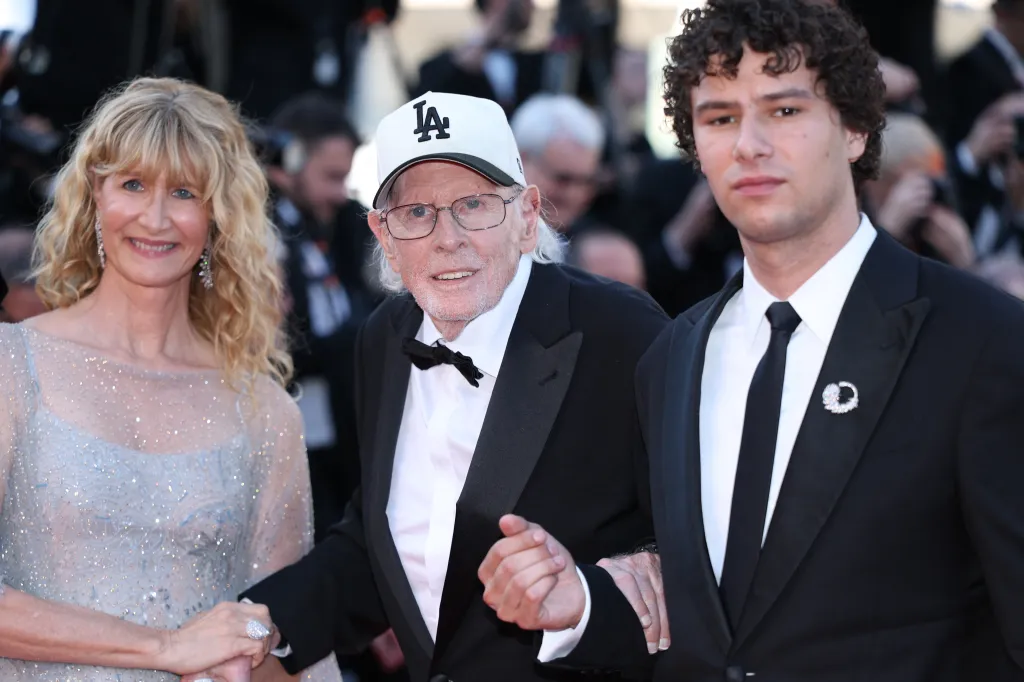 Laura Dern, Bruce Dern, and a younger man in tuxedos on the red carpet at the Cannes Film Festival.