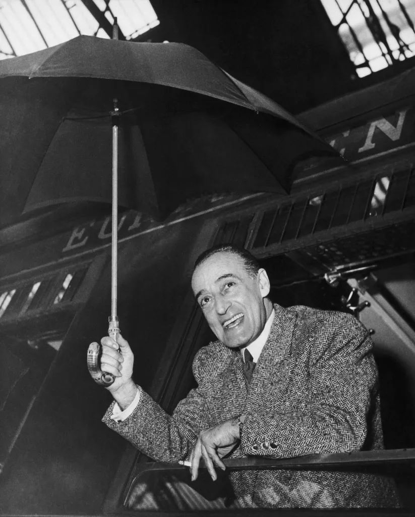 Black and white photo of Italian comic actor Toto, holding an umbrella and smiling.
