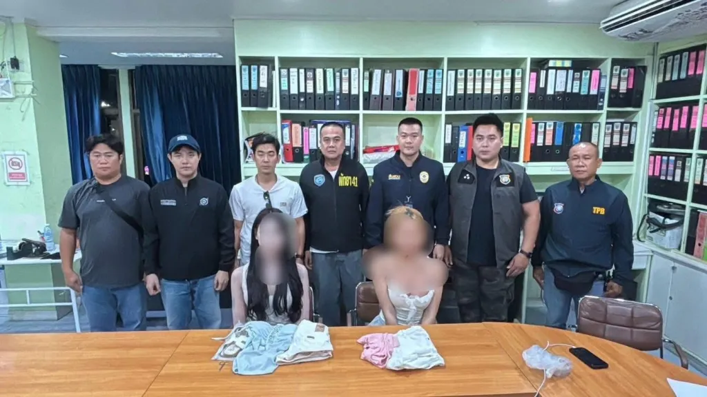 Law enforcement officers and two women in an office, items on a table in front of them.