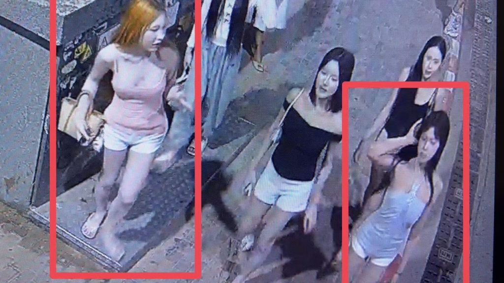 Surveillance footage showing three women walking down a street.