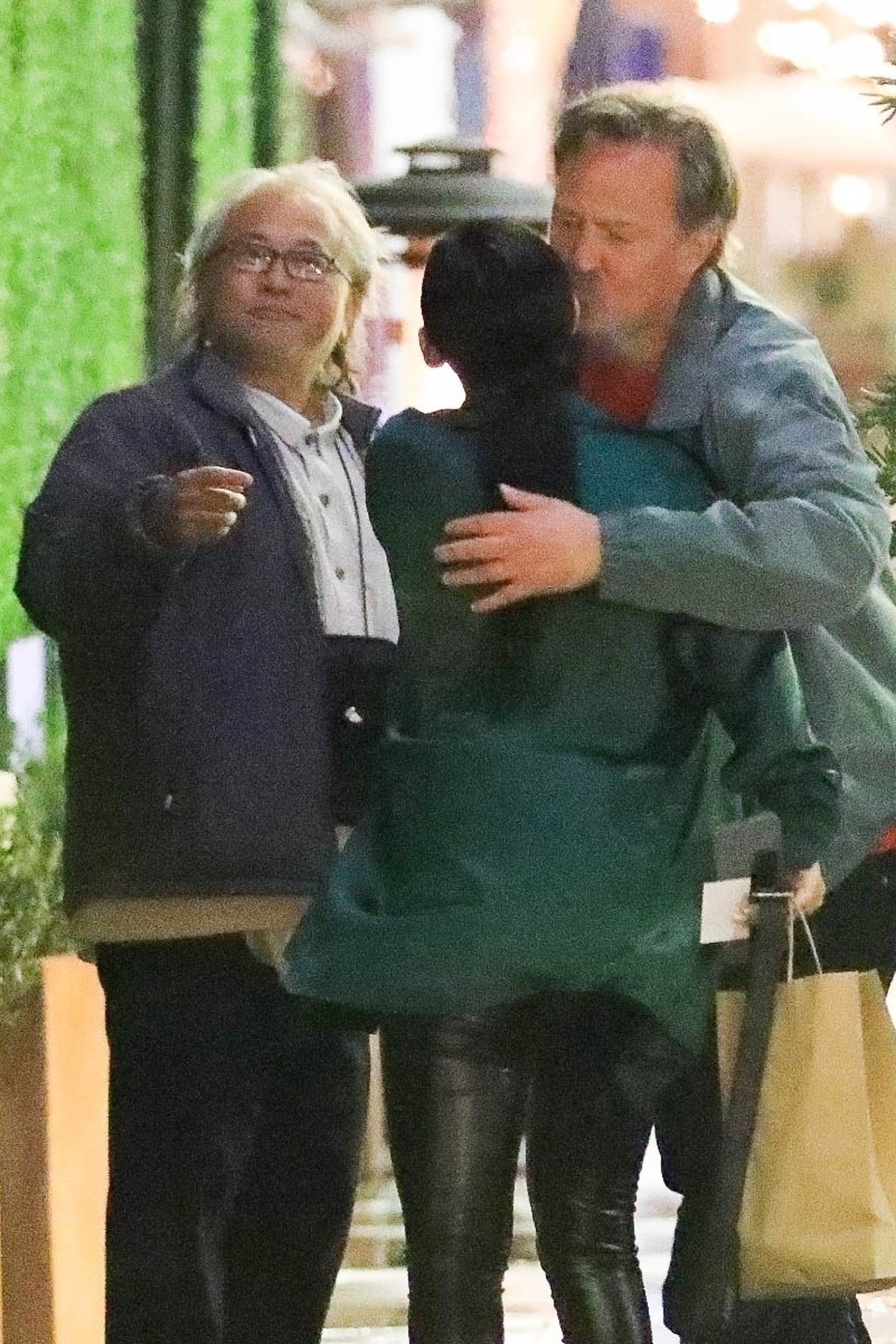 Matthew Perry hugging a woman goodbye as Kenneth Iwamasa stands nearby.