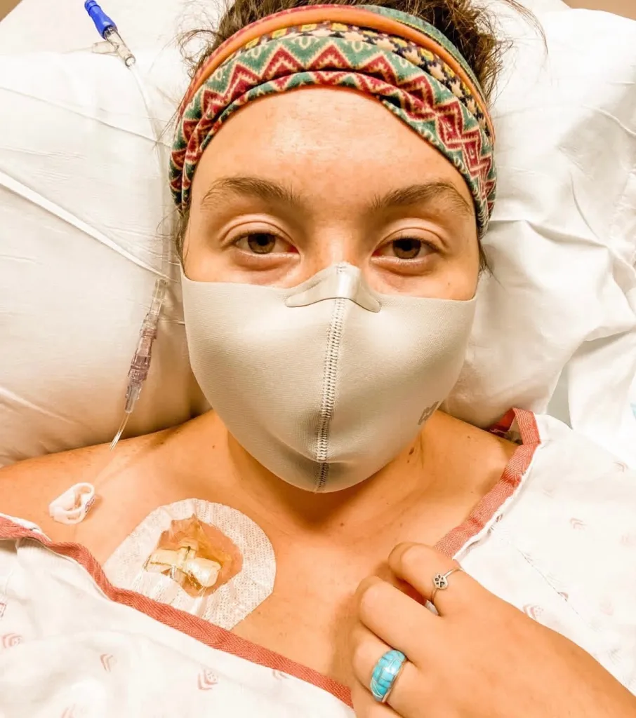 Emma Widmar with a medical mask and an IV line, representing autoimmune disease.