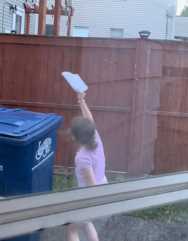 Eight-year-old girl Madeline throwing a paper airplane over her fence.