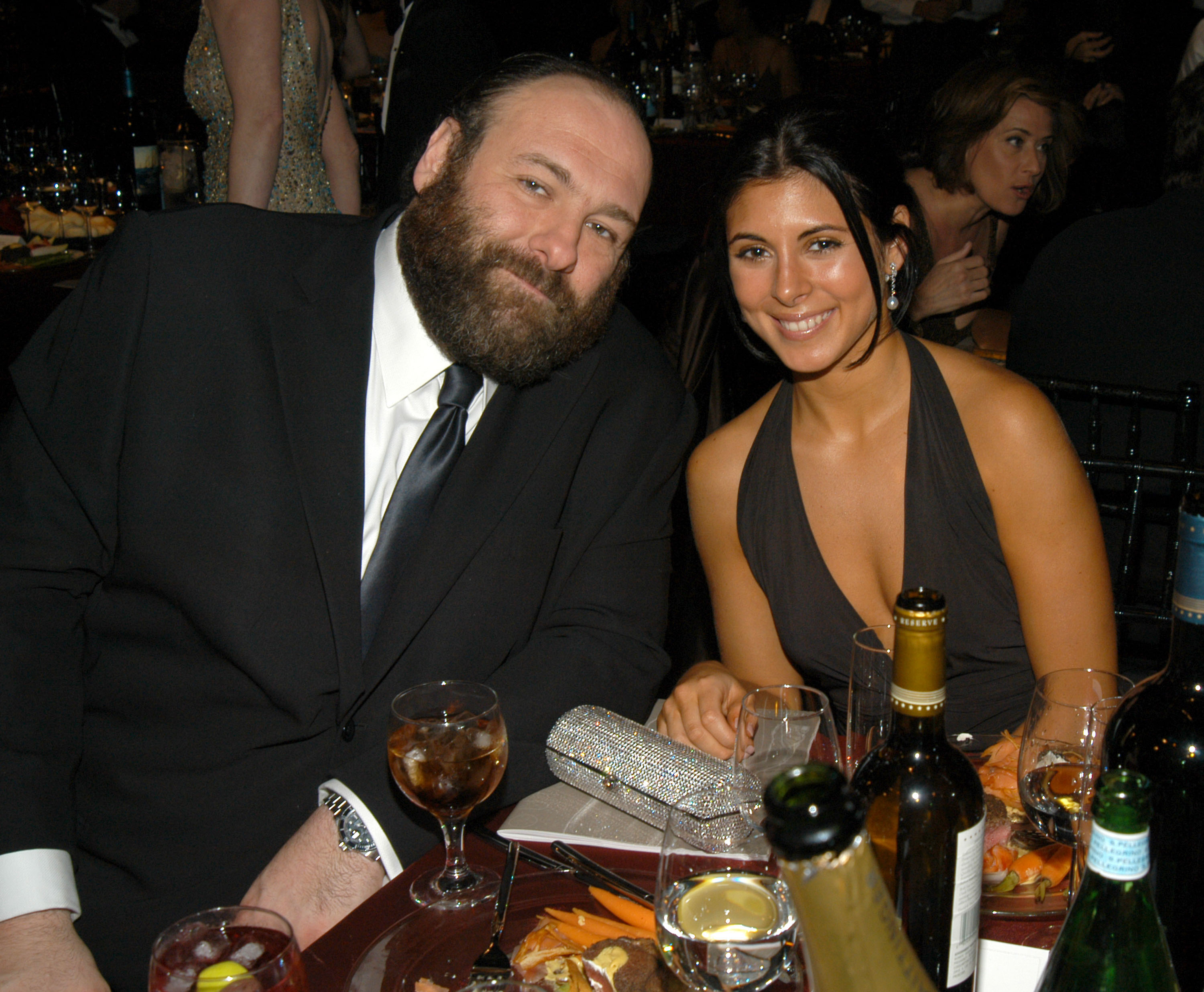 James Gandolfini and Jamie-Lynn Sigler sitting at a table with drinks.
