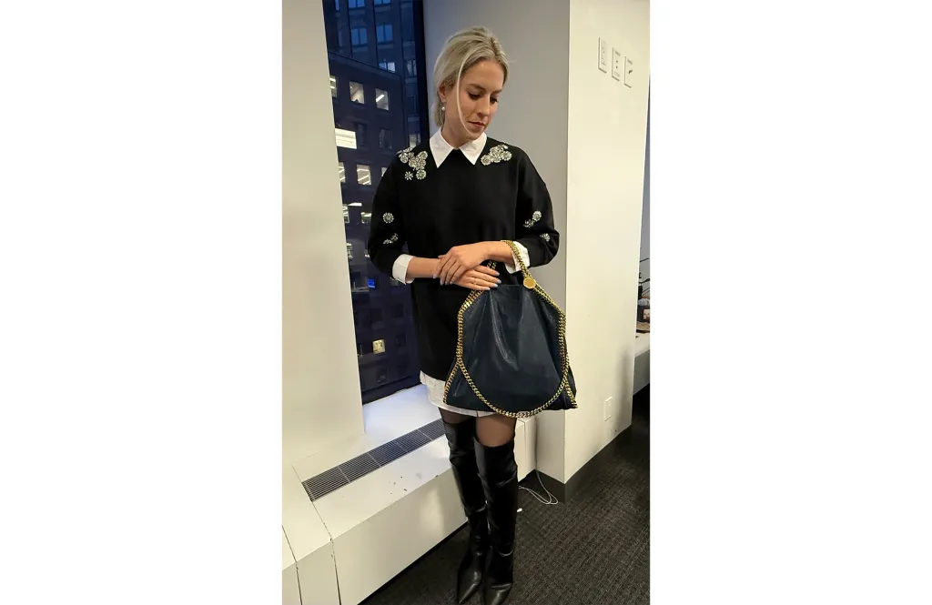 A woman wearing a black dress and boots and a Stella McCartney