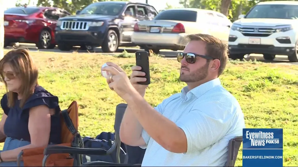 Justin Ritchie filming a video with his phone while holding a baseball.