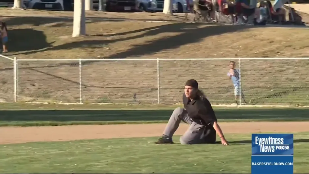 Sawyer Sparks, a Bakersfield Little League umpire, crouched on the field in gray pants and a black shirt.