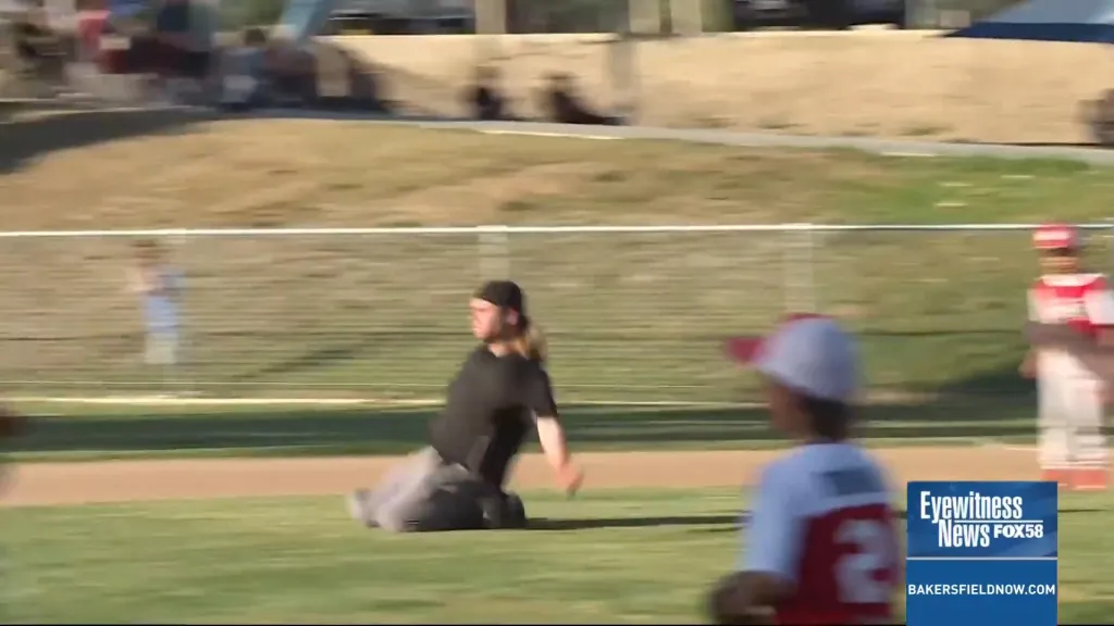 Little League umpire Sawyer Sparks crouching on a baseball field.