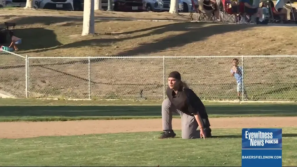 Umpire Sawyer Sparks kneels on a baseball field.