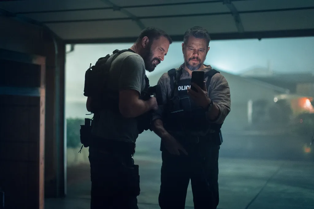 Ben Affleck as Det Sergeant JD Byrne and Matt Damon as Lieutenant Dane Dumars looking at a cell phone.