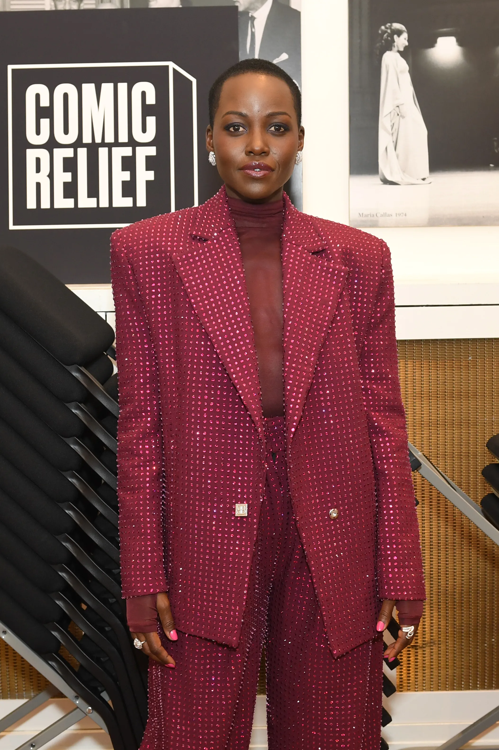 Lupita Nyong'o in a shimmering burgundy pantsuit at a Comic Relief event.