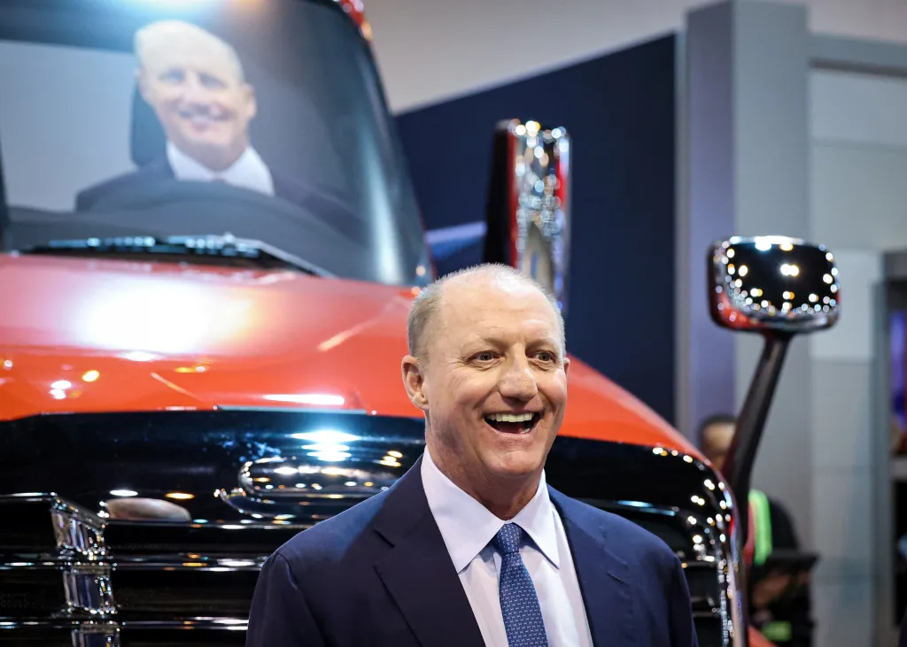 Berkshire Hathaway CEO Greg Abel smiles broadly, standing in front of a red truck.