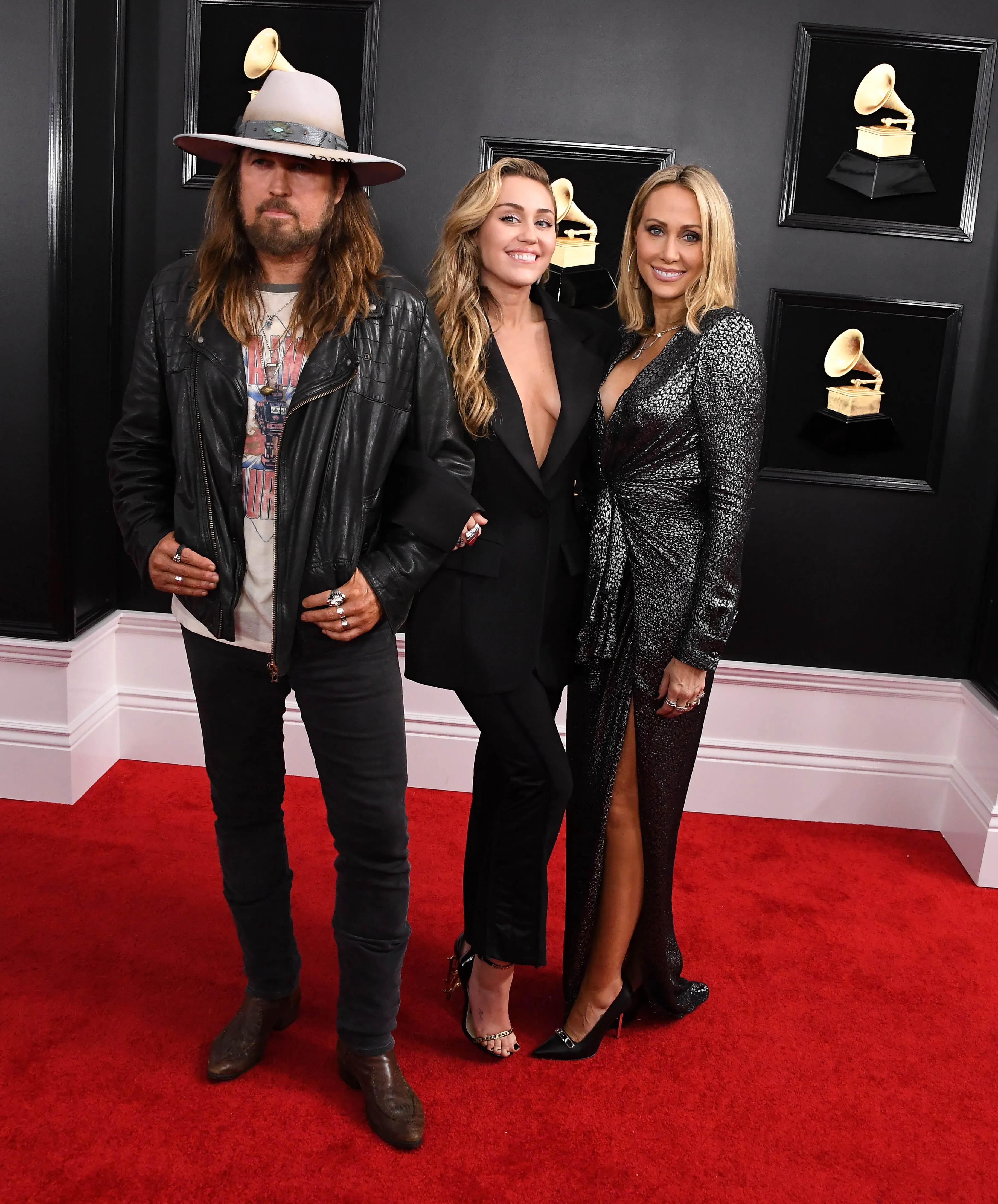 Billy Ray Cyrus, Miley Cyrus, and Tish Cyrus on a red carpet.