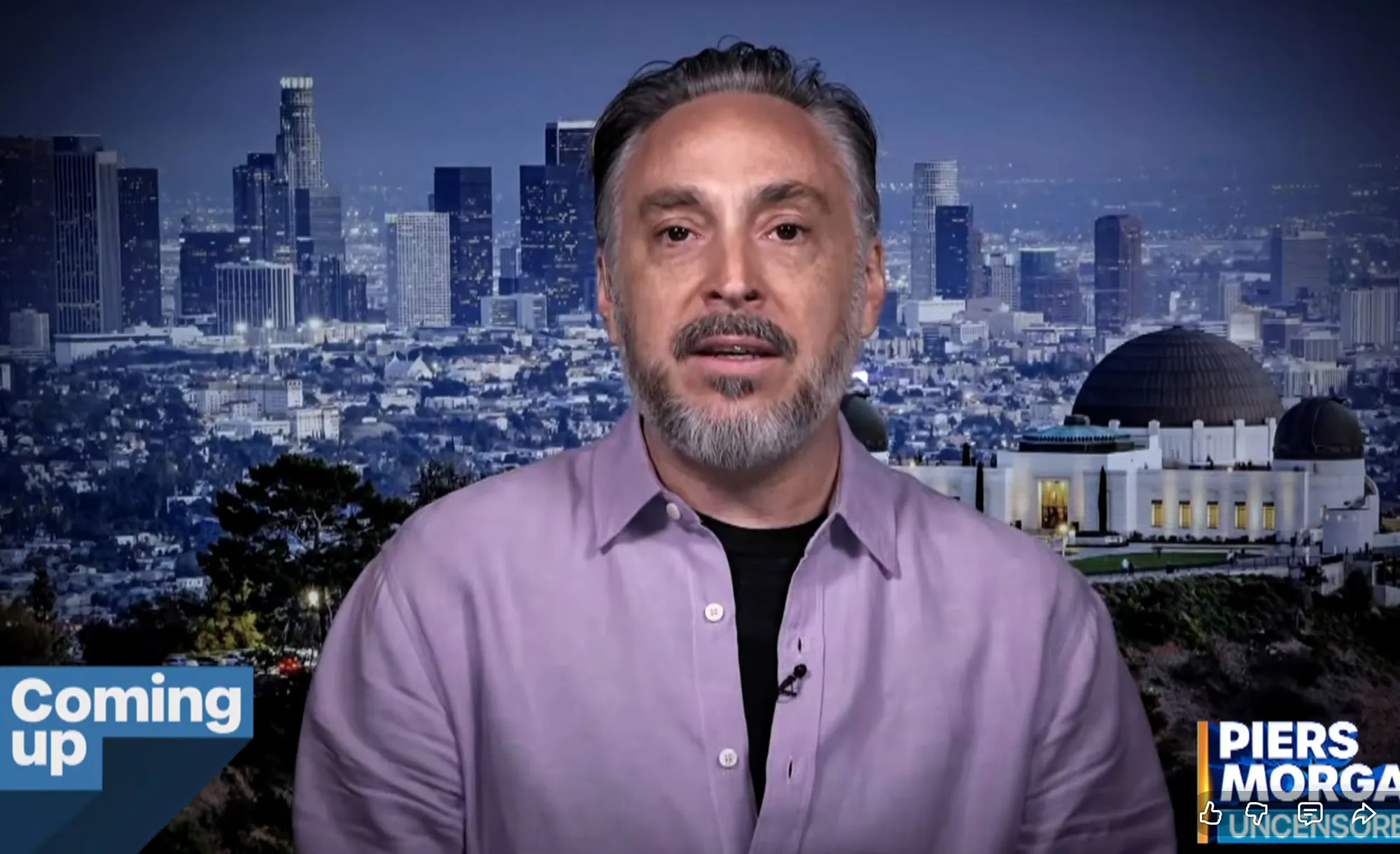 Adam Mondschein speaking in front of a Los Angeles cityscape at night.