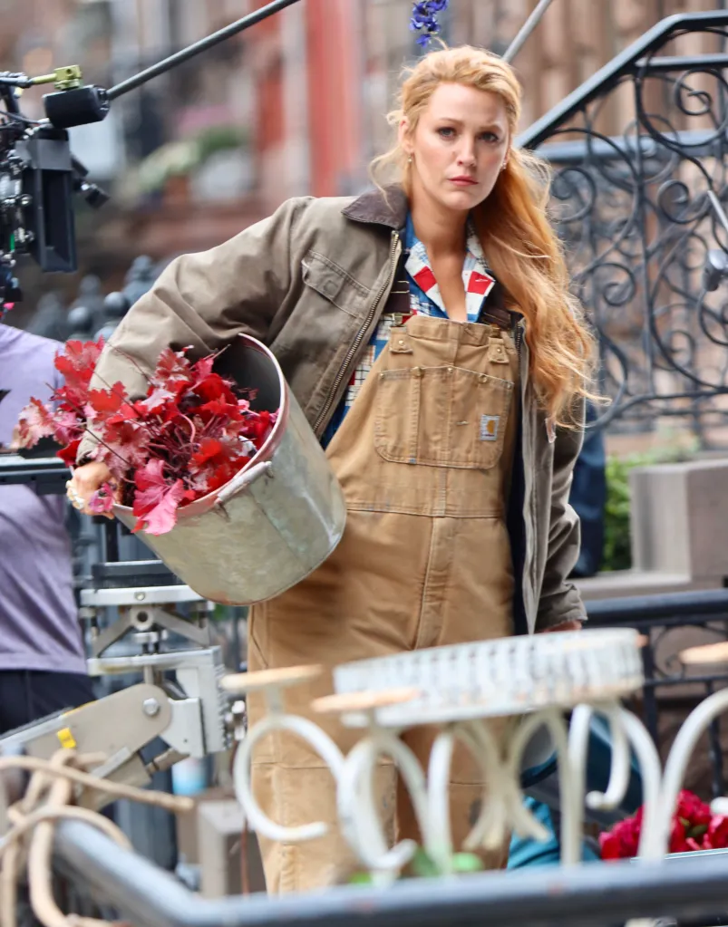Blake Lively in overalls carrying a bucket of plants on the set of 