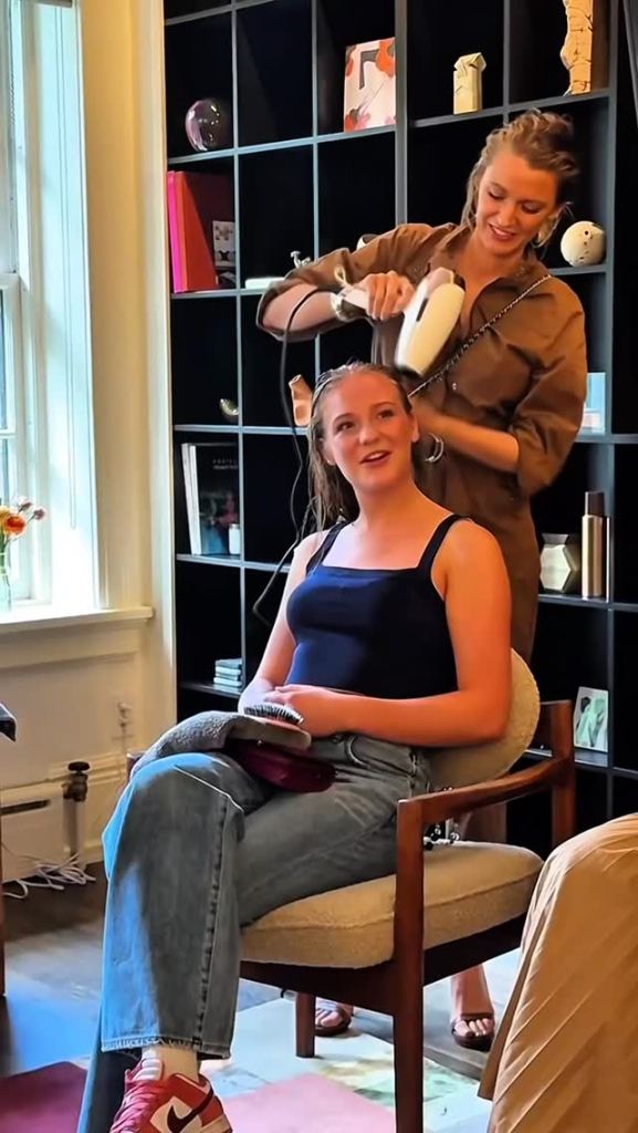 A woman blow-drying another woman's wet hair.
