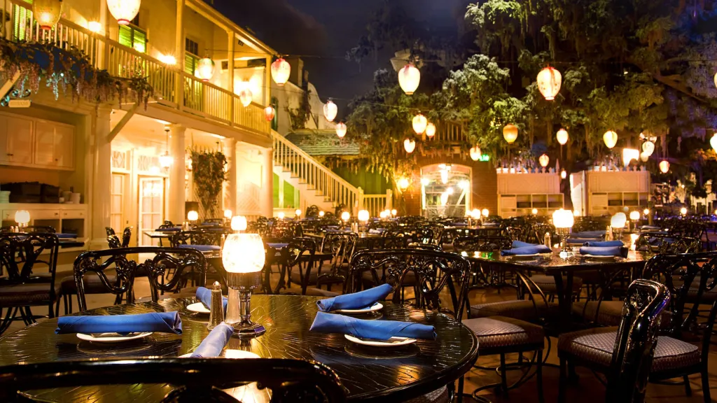 The Blue Bayou Restaurant at Disneyland Park, featuring tables set with blue napkins, illuminated by many lanterns, at night.