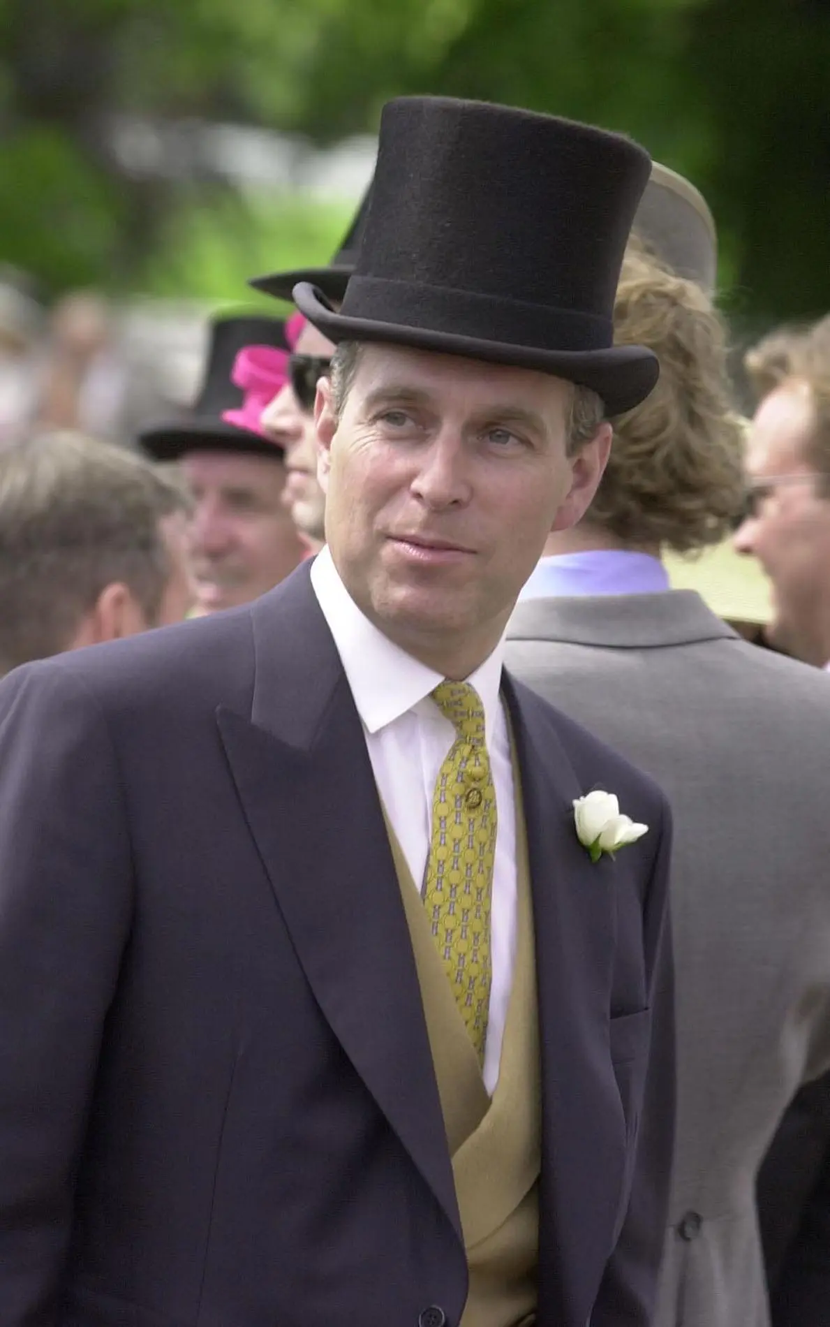 Prince Andrew, Duke of York, wearing a top hat, suit, and yellow tie.