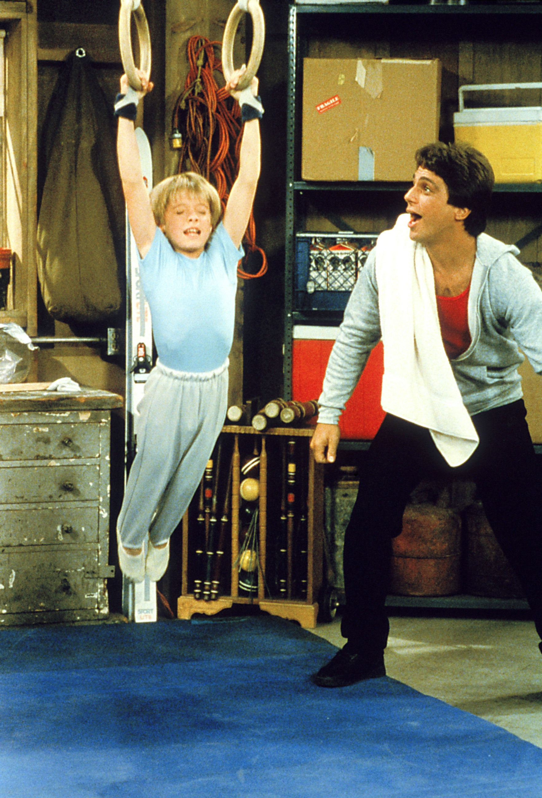 Danny Pintauro on gymnastics rings as Tony Danza watches.