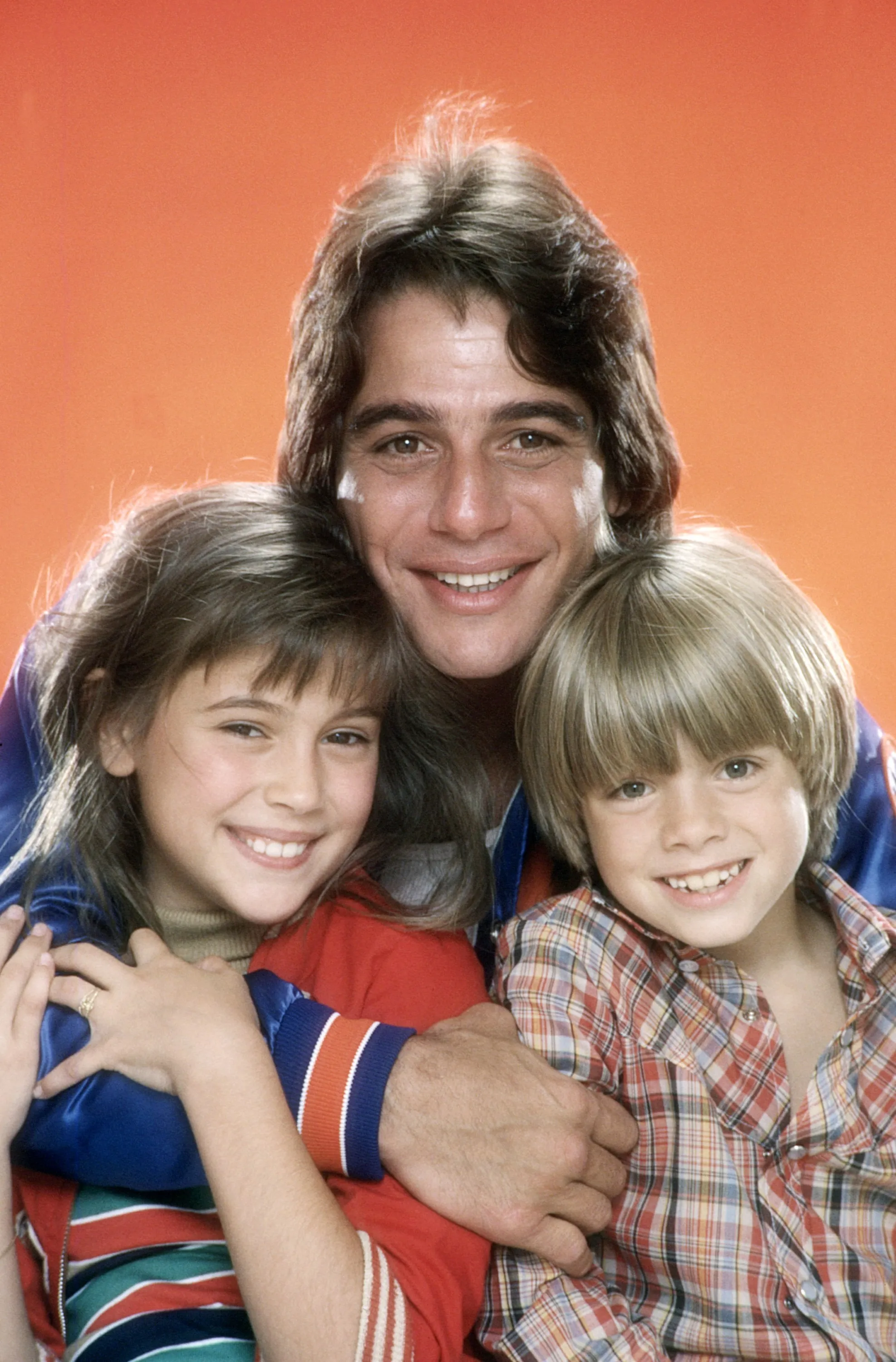 Tony Danza, Alyssa Milano, and Danny Pintauro smiling and embracing.