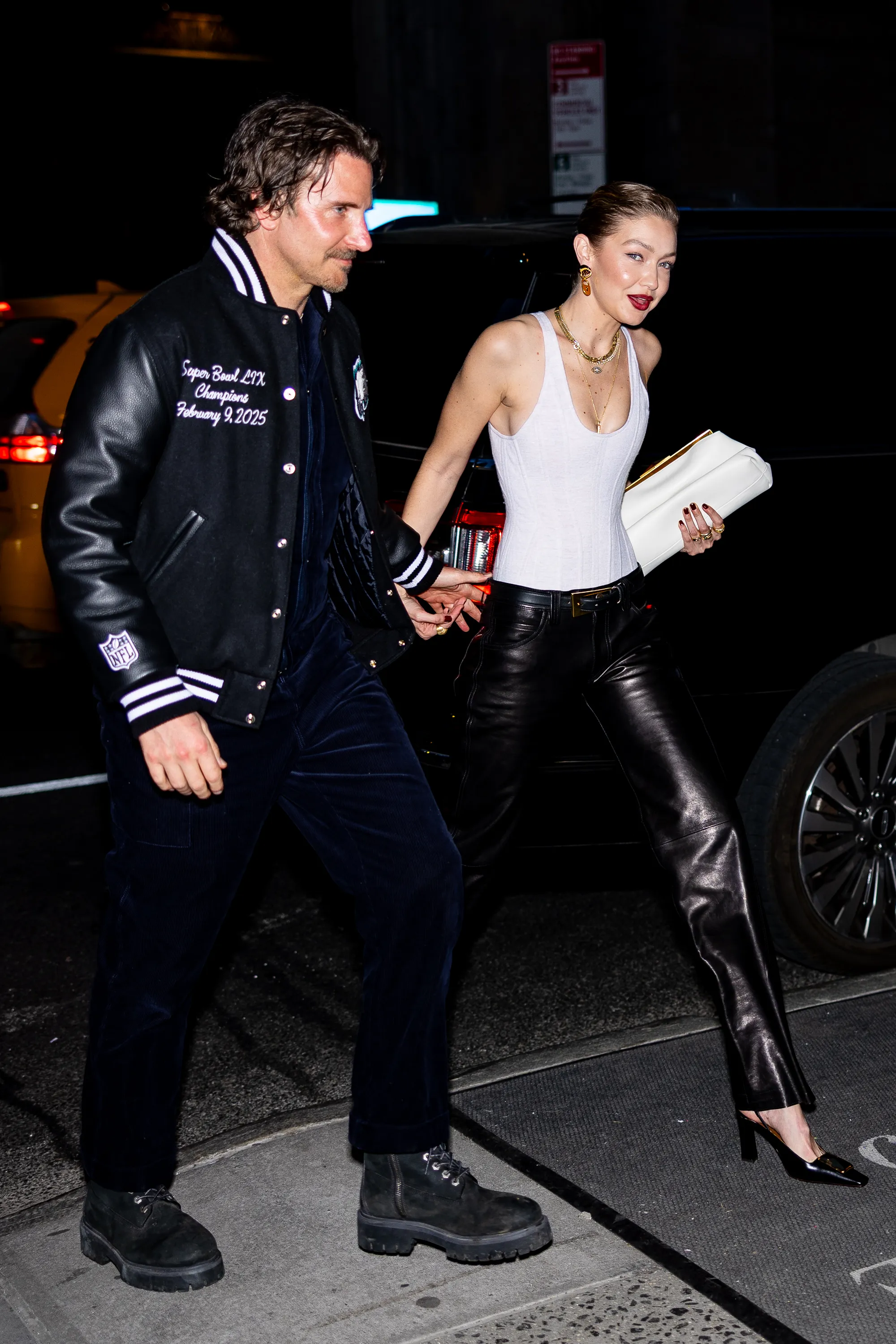 Bradley Cooper and Gigi Hadid walk side-by-side at night.