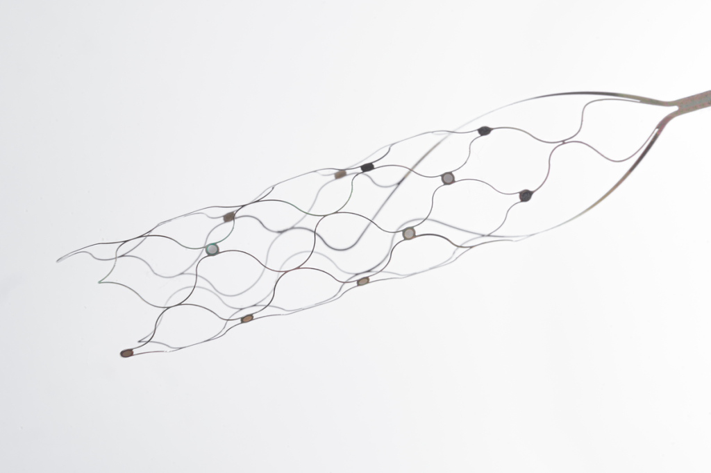 A metallic stent with a wavy pattern and small circular sensors, against a white background.