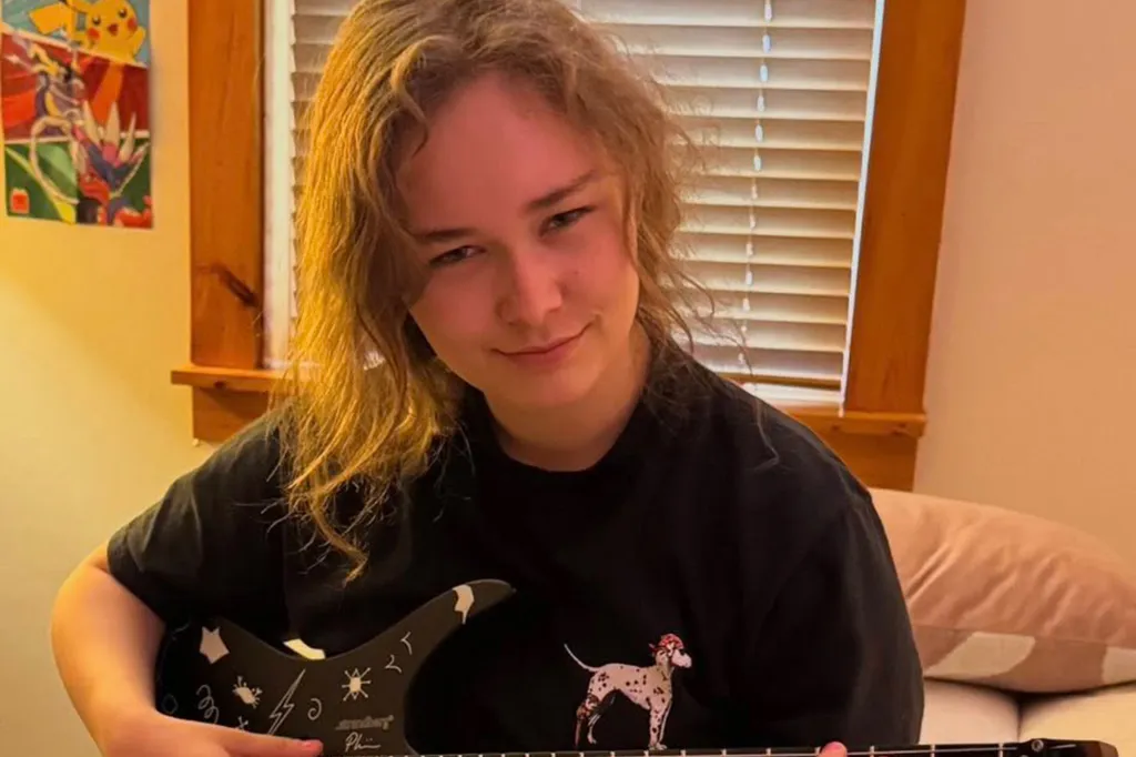 Breanne Keane holding a black electric guitar with white designs.
