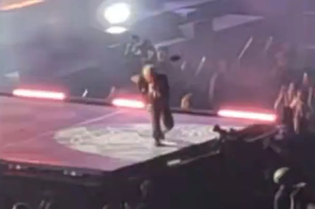 A blurry concert photo of Bring Me the Horizon frontman Oli Sykes on stage at the moment he was hit by a thrown phone.