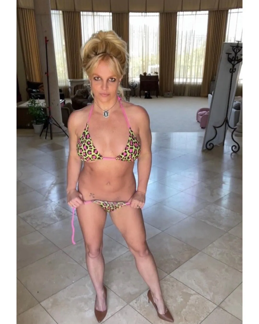 Britney Spears posing in a leopard print bikini and high heels in her home.