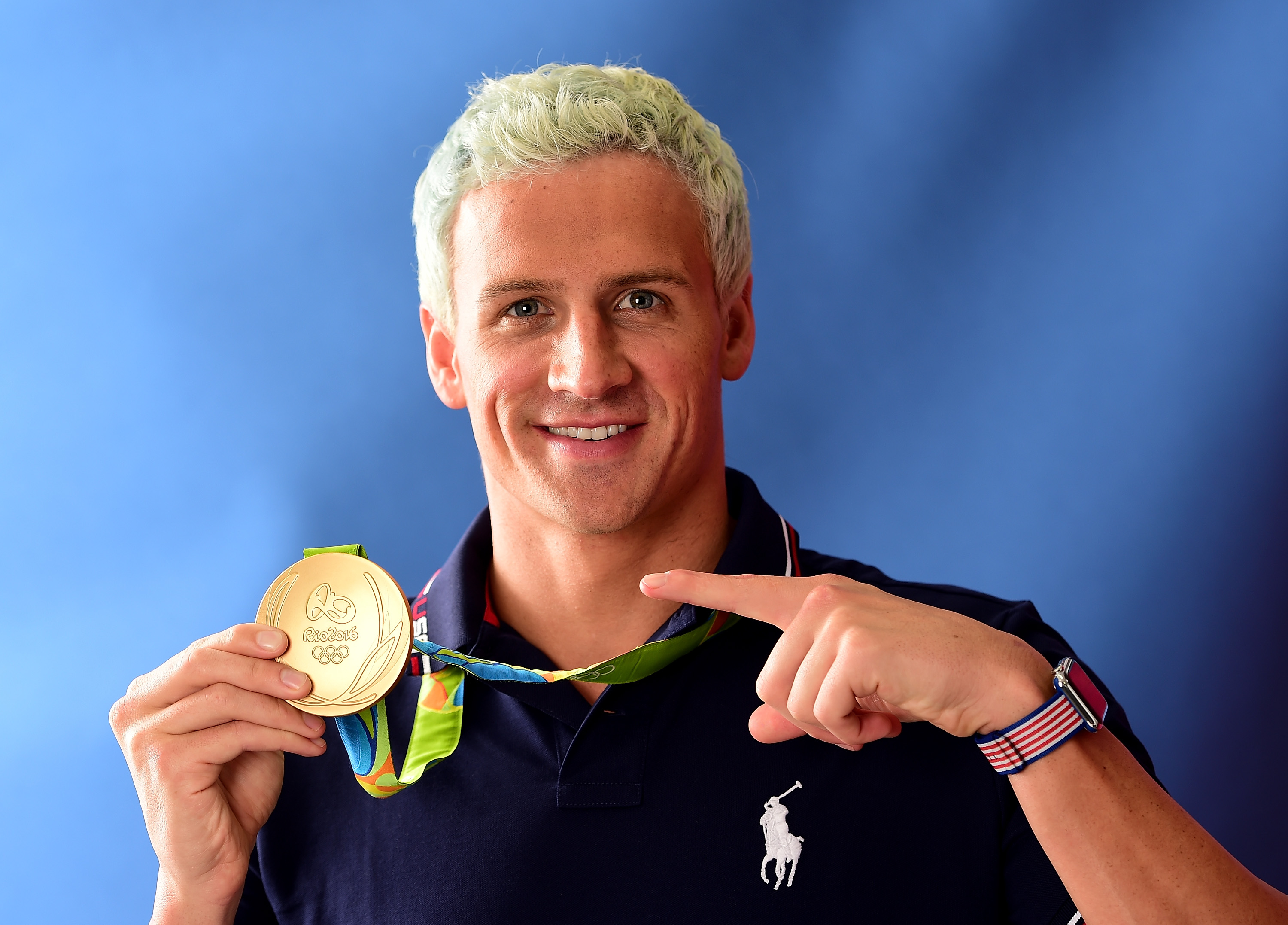 Ryan Lochte holding his Olympic gold medal.