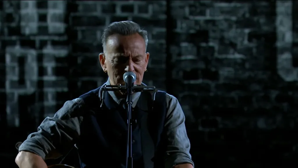 Bruce Springsteen performs while playing guitar and harmonica.