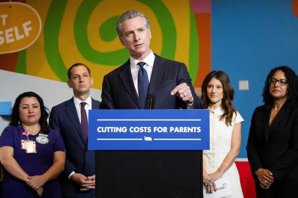 California Governor Gavin Newsom at a press conference with the text 