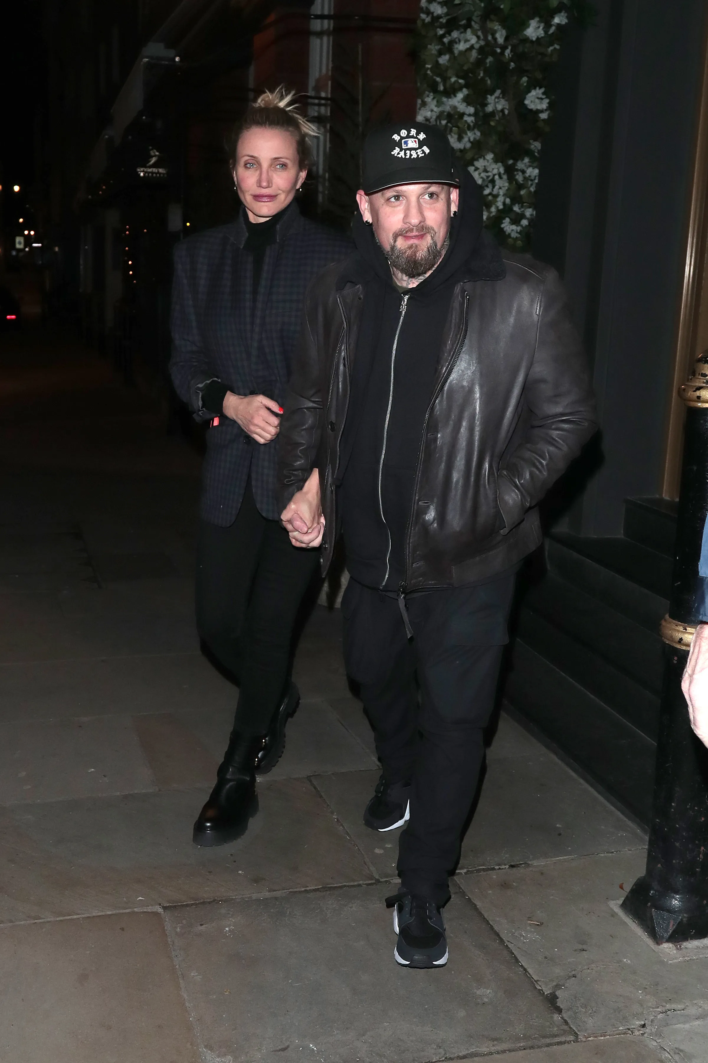 Cameron Diaz and Benji Madden walking together at night, holding hands.