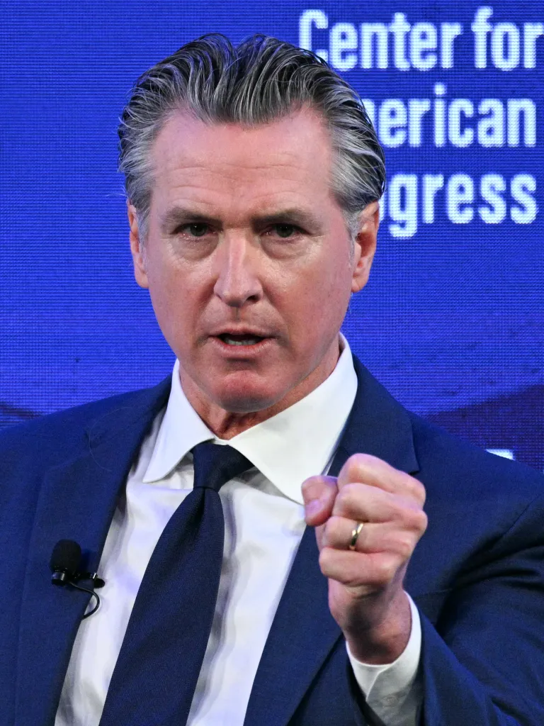 California Governor Gavin Newsom speaking at the Center for American Progress conference, with his right hand in a fist.
