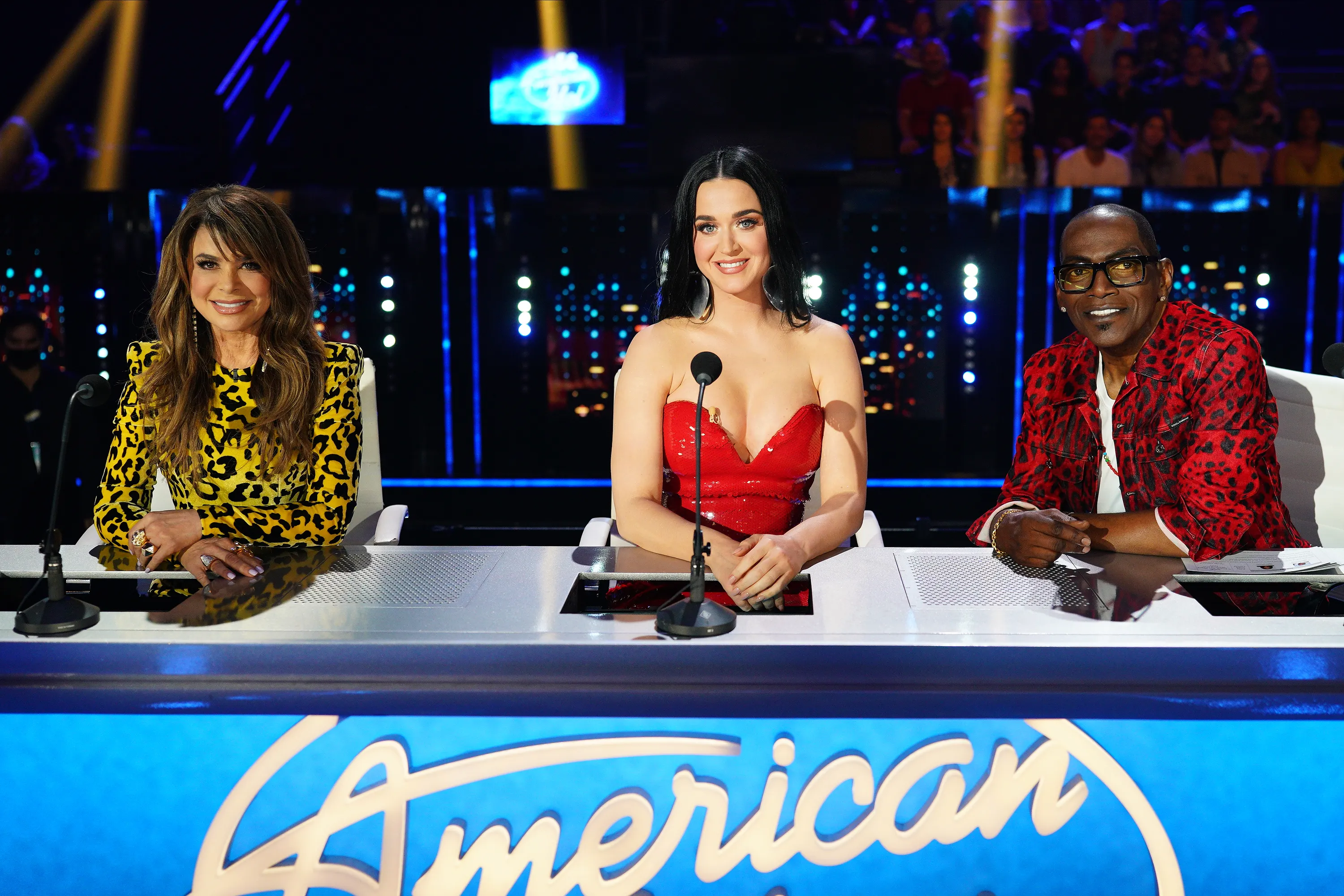 Paula Abdul, Katy Perry, and Randy Jackson posing behind the judges' table for American Idol.