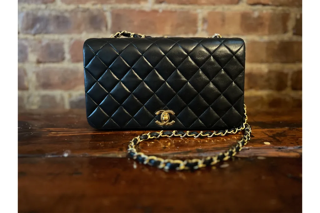 A black Chanel purse on a wooden surface.