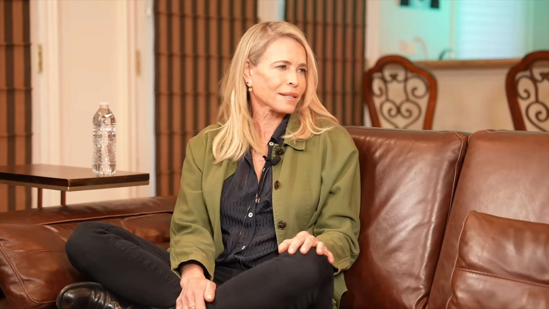 Chelsea Handler sitting on a brown leather couch.