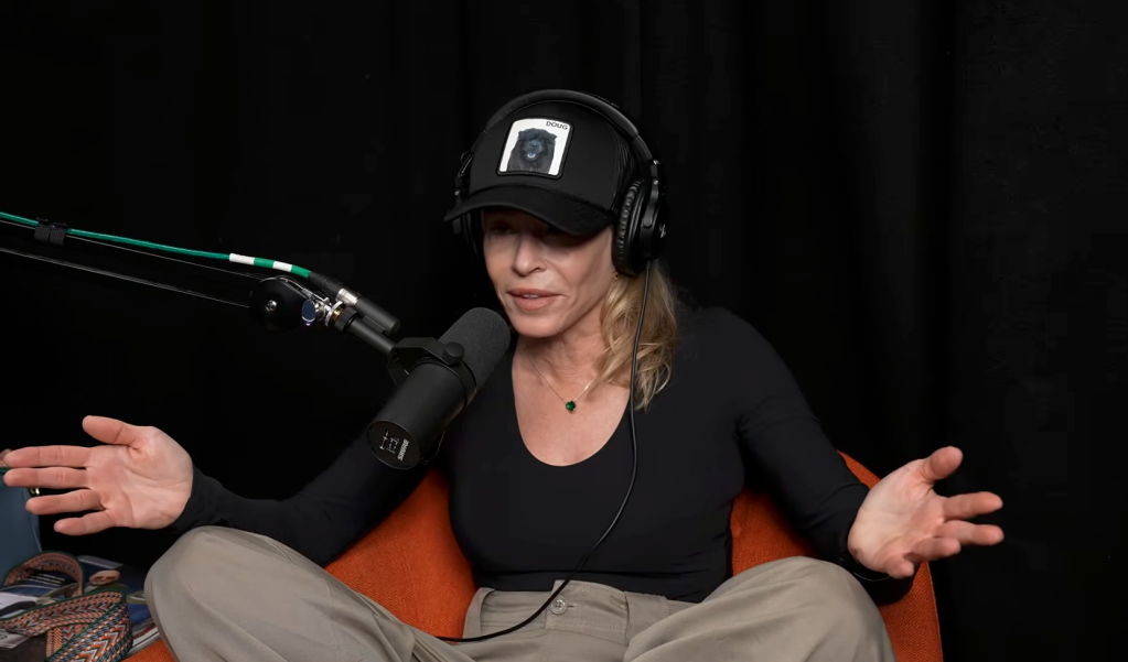 Chelsea Handler speaking into a microphone while wearing headphones and a hat.