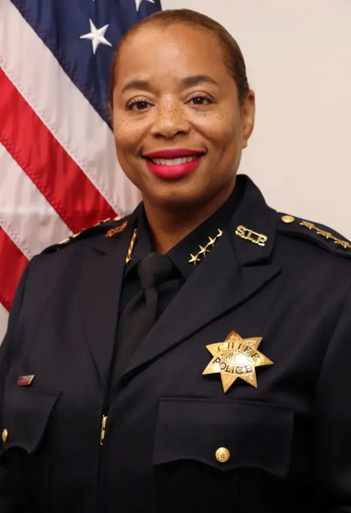 Chief Angela Averiett smiling in her police uniform, with an American flag behind her.