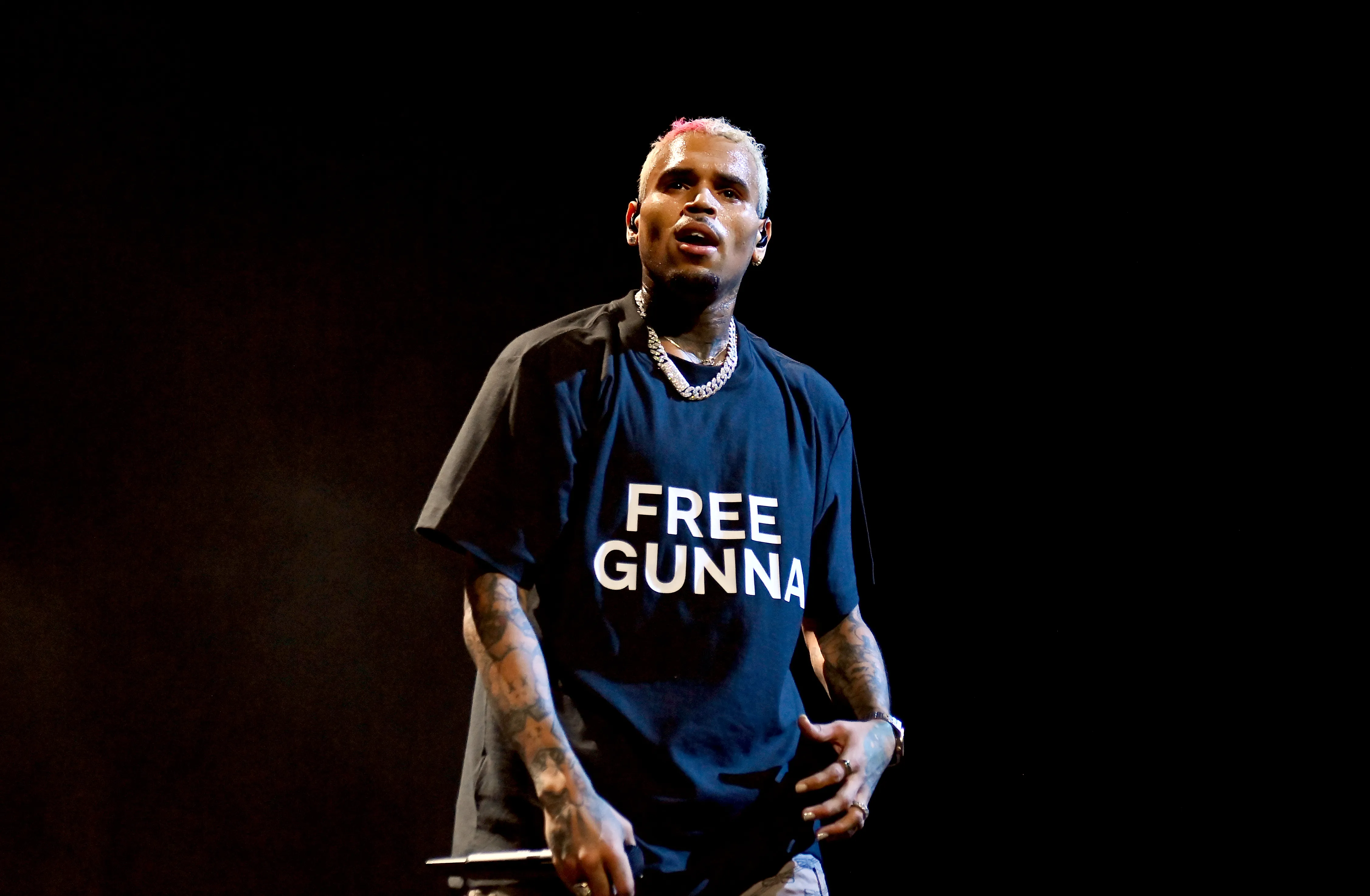 Chris Brown performing onstage in a black t-shirt that says 