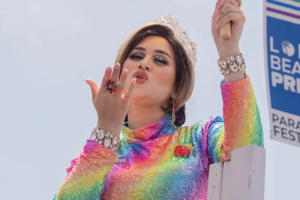 A performer in a rainbow-sequined dress and crown blows a kiss at the Long Beach Pride Parade.