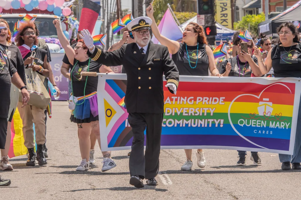 People in a Long Beach Pride Parade holding a banner that reads
