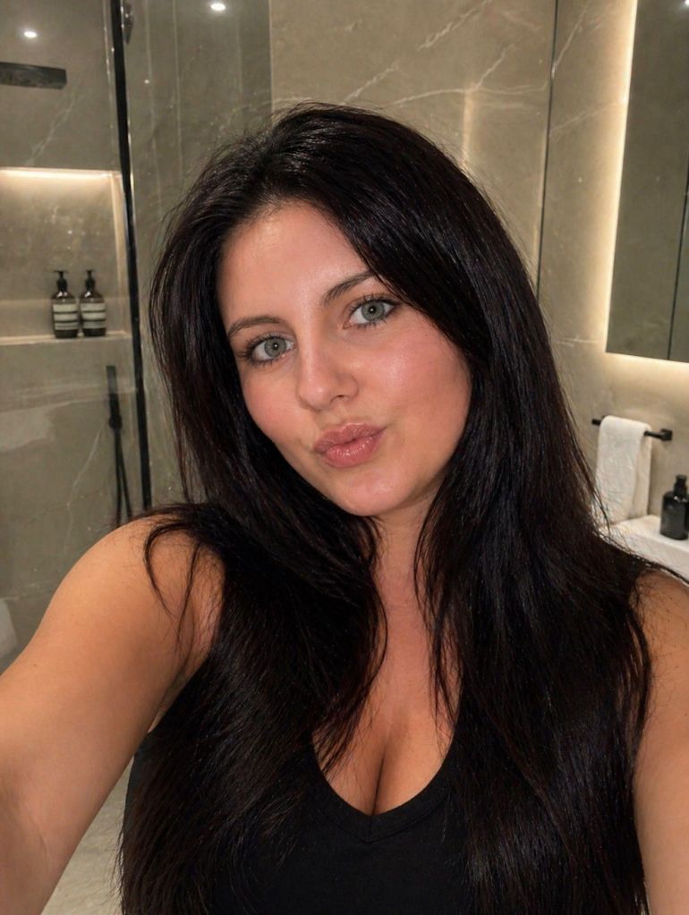 Clarissa Mias, a dark-haired woman, posing for a selfie in a bathroom.